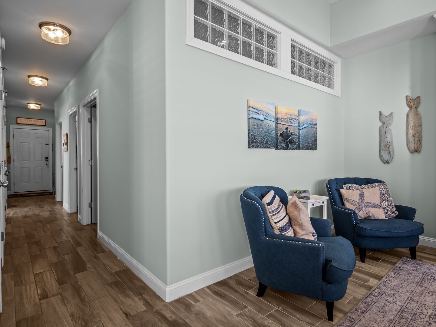 Sink into these plush navy chairs in your bright living space, where coastal artwork and warm lighting create the perfect spot to unwind.