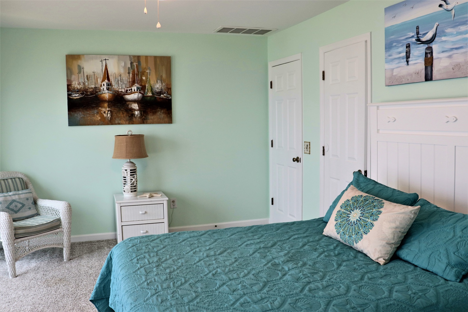 Your peaceful bedroom features coastal artwork and teal bedding, creating a tranquil seaside retreat.