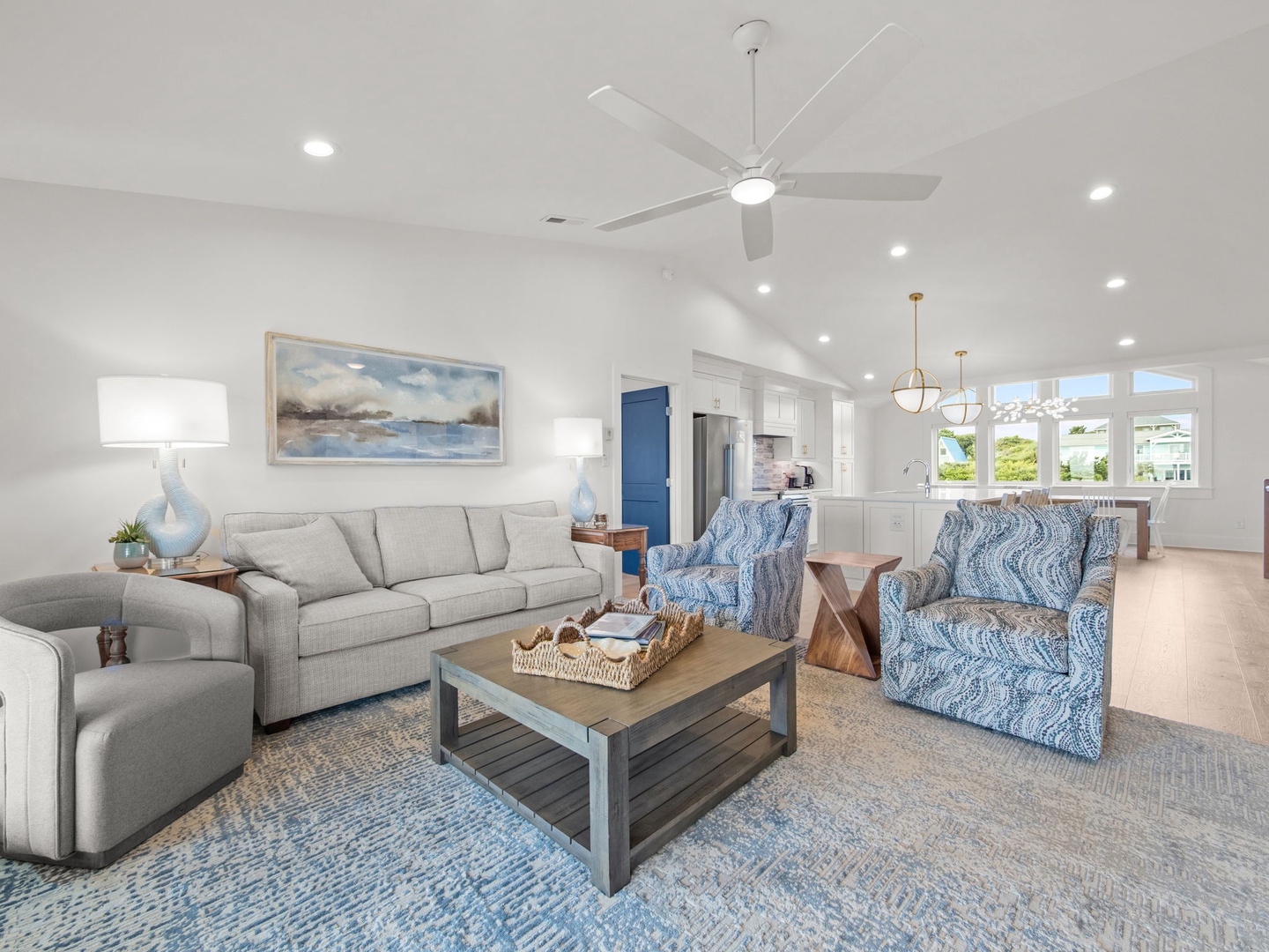 Relax in your bright, open living space with coastal-inspired furnishings, soft blue accents, and a ceiling fan for perfect comfort.