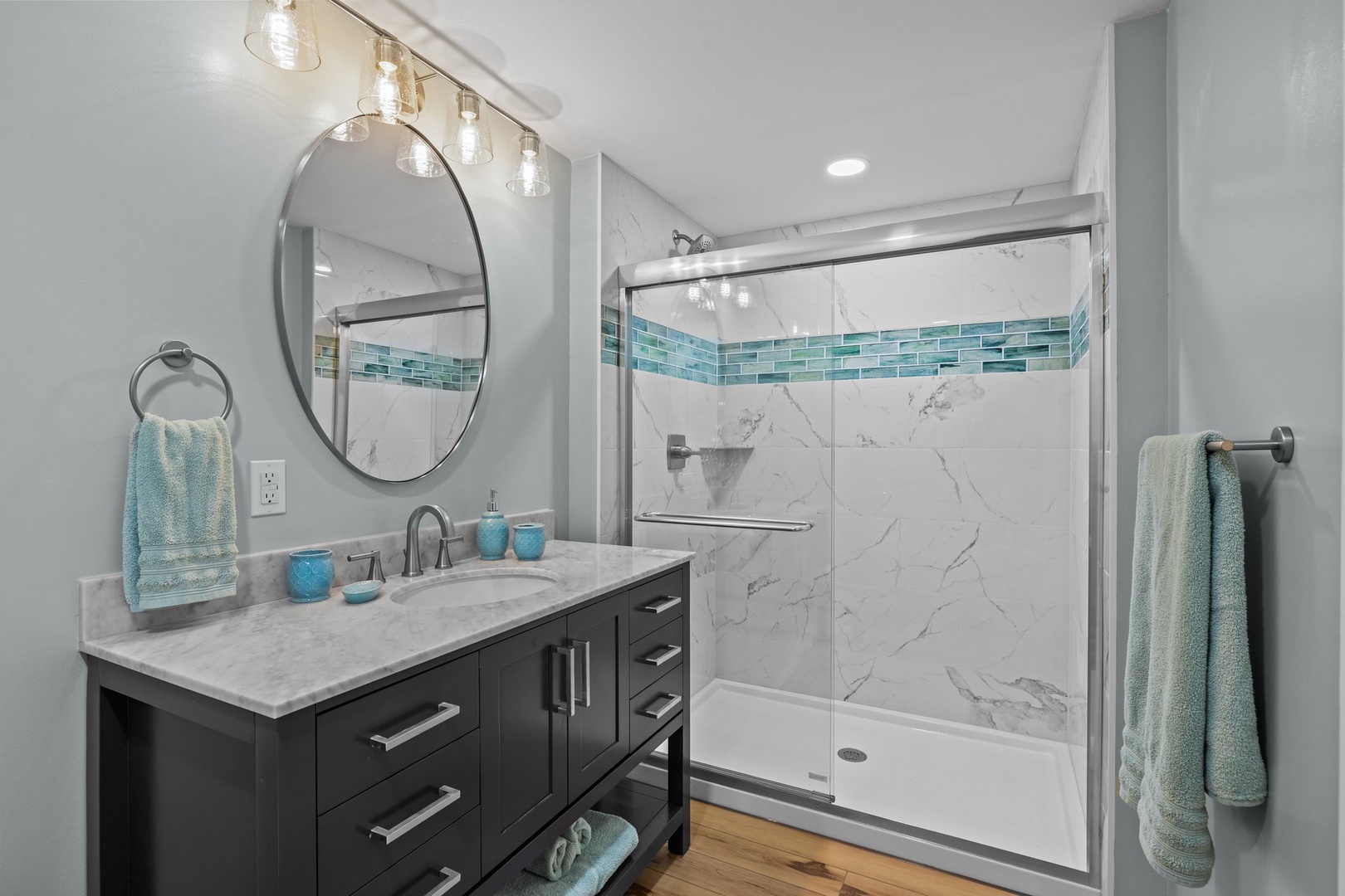 Unwind in your spa-like bathroom with beautiful blue accent tiles, elegant marble shower, and thoughtful amenities for a perfect retreat.