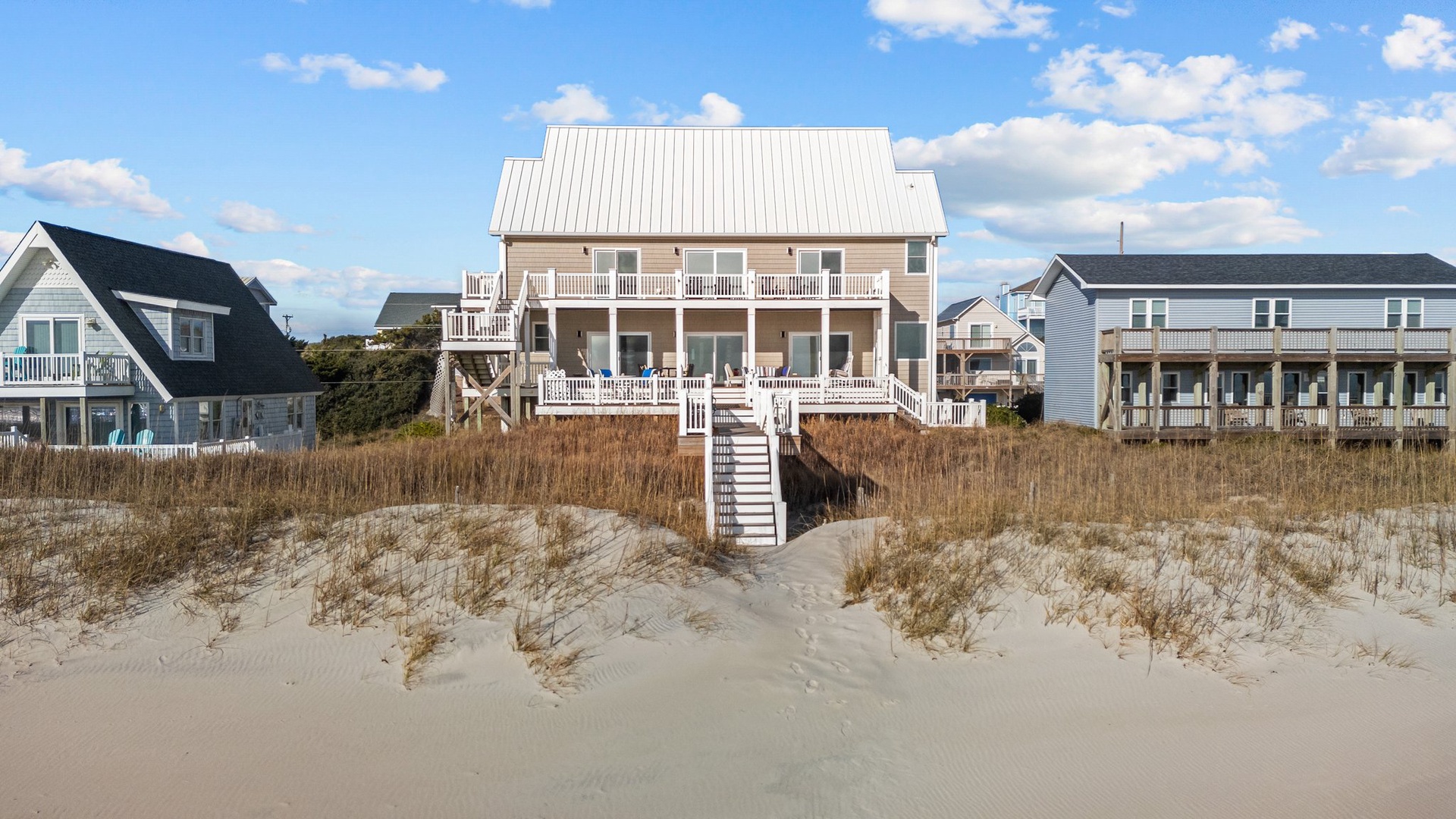 Charming beachfront home with multiple decks overlooking pristine sandy shores and coastal dunes.