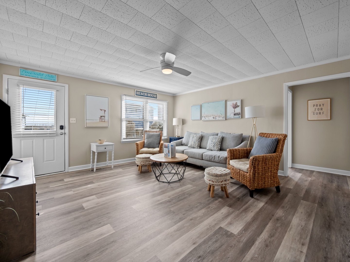 Sink into the plush gray sofa in your beautifully designed living room, where coastal charm meets modern comfort under soaring whitewashed ceilings.