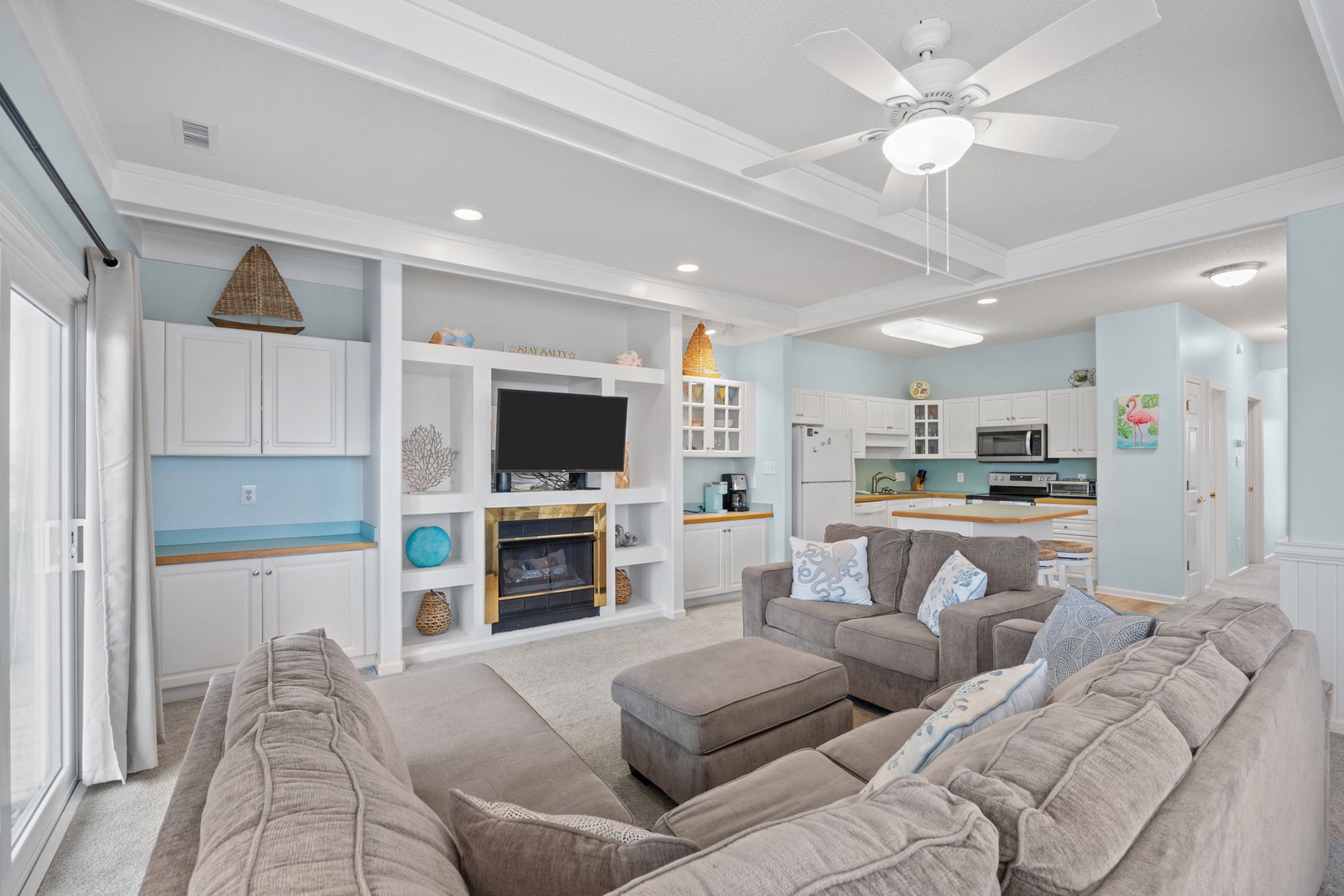 Sink into plush sectional seating in your bright, open living space with coastal touches and modern kitchen nearby.