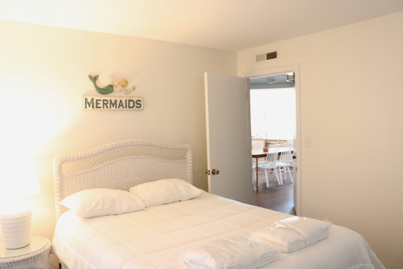 Drift off to sleep surrounded by coastal charm in this cozy bedroom with whimsical mermaid decor and crisp white linens.