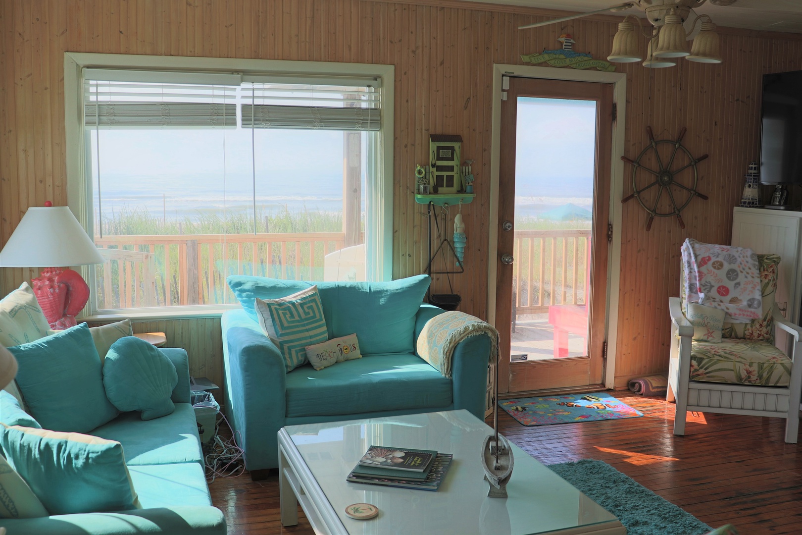 Unwind in your coastal living room with turquoise sofas and ocean views streaming through large windows and patio doors.
