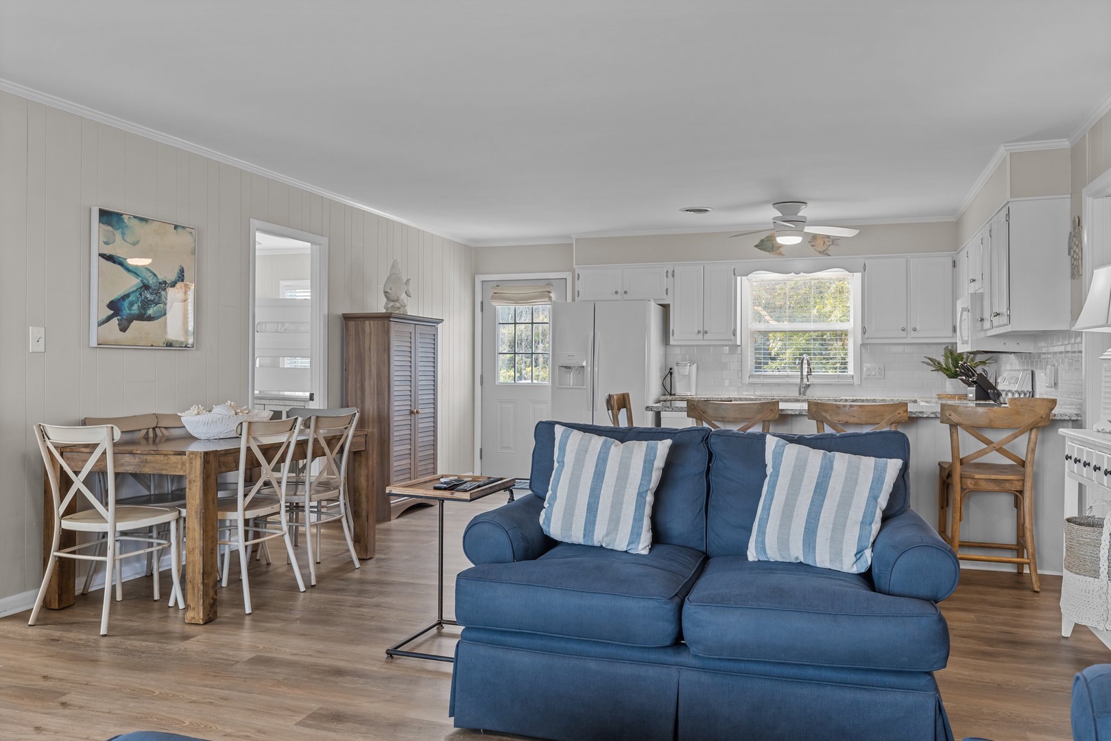 Sink into the plush blue sofa and enjoy your open-concept retreat with coastal charm, where kitchen, dining, and living flow seamlessly together.