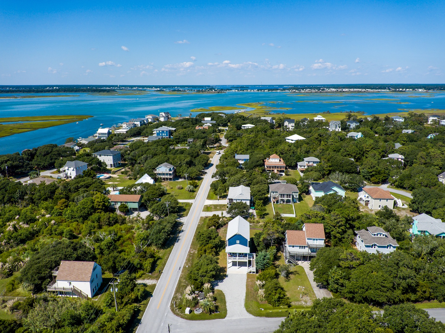 Aerial view of a coastal community nestled between lush trees and sparkling waterways, offering peaceful island living.