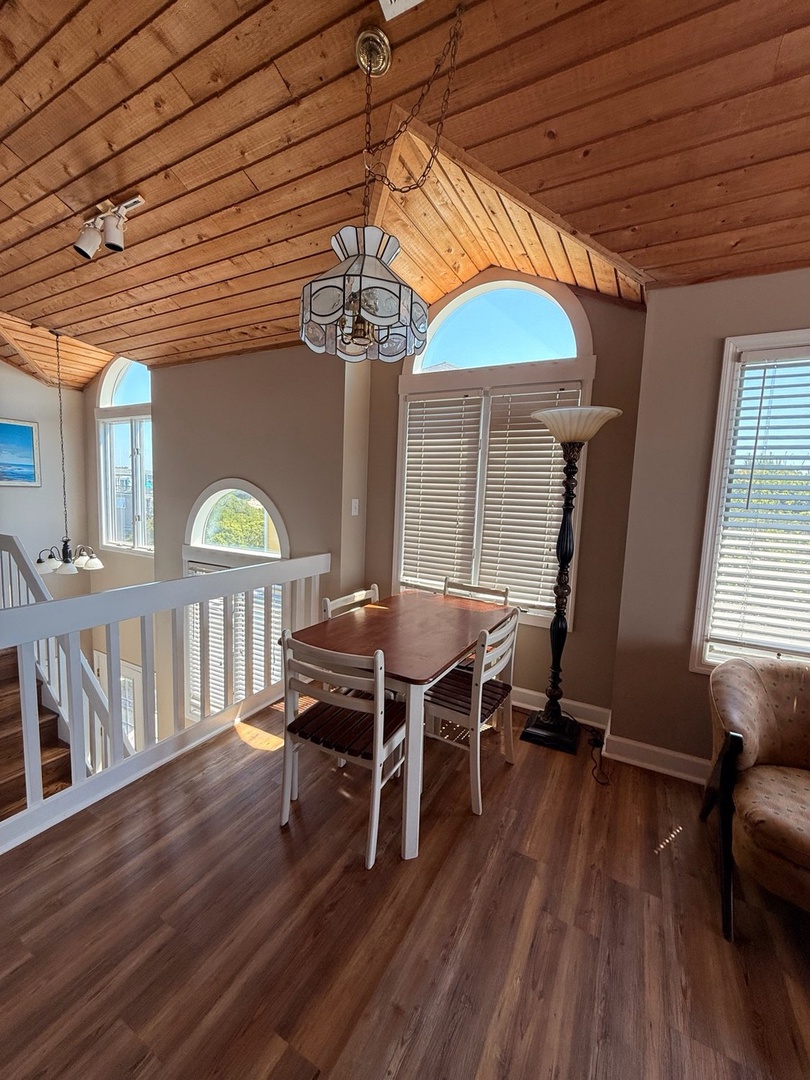 Gather around your own dining table beneath vaulted wood-plank ceilings and abundant natural light from arched windows, creating the perfect setting for morning coffee or evening meals together.