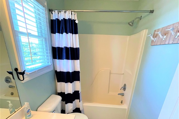 Step into your bright, airy bathroom with modern shower and cheerful nautical-striped curtain. The fresh space offers everything you need.