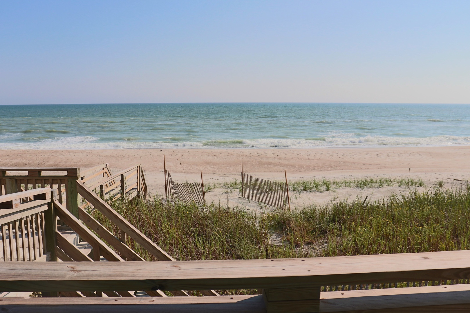 Pristine oceanfront beach with wooden boardwalk access just steps from the property.