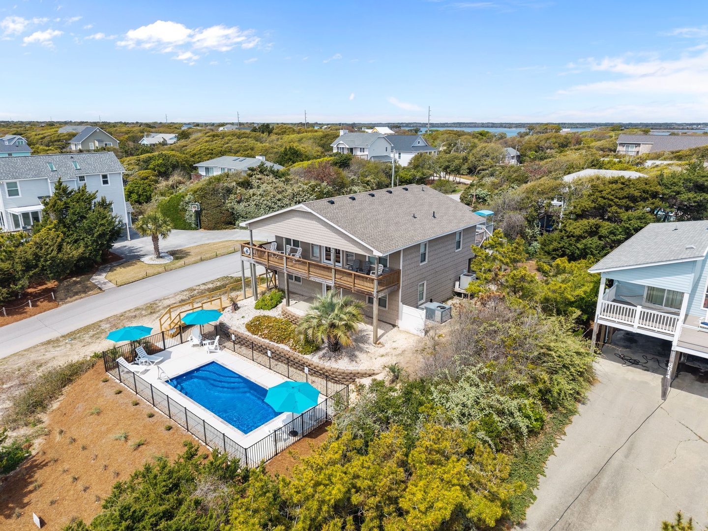 Coastal vacation home with private pool and deck surrounded by lush landscaping in a peaceful neighborhood setting.