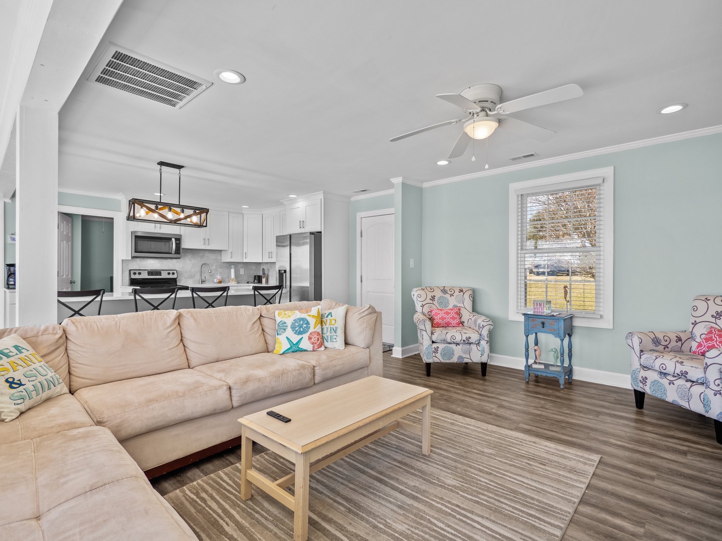 Unwind in your bright, open living space featuring plush seating, coastal decor, and modern kitchen—perfect for relaxing after beach adventures.