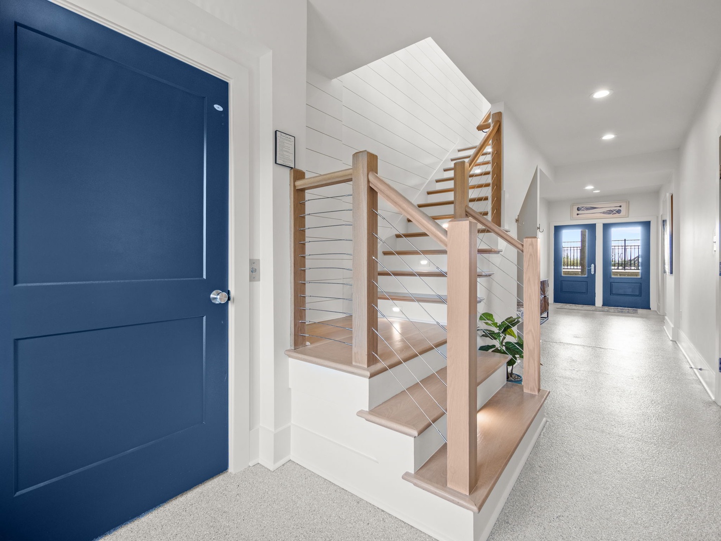 Step into this bright, modern entryway where coastal charm meets contemporary design—crisp whites and ocean blues create your perfect coastal retreat.