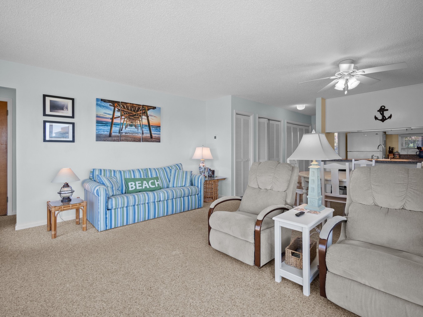 Relax in your coastal-themed living room with comfortable seating, beach artwork, and a ceiling fan to keep you cool during your stay.