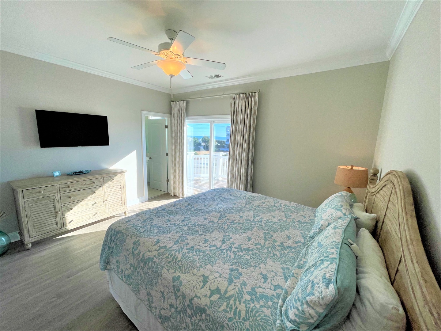 Your serene bedroom offers coastal comfort with ocean-inspired linens, gentle ceiling fan breezes, and your own private balcony for peaceful moments.