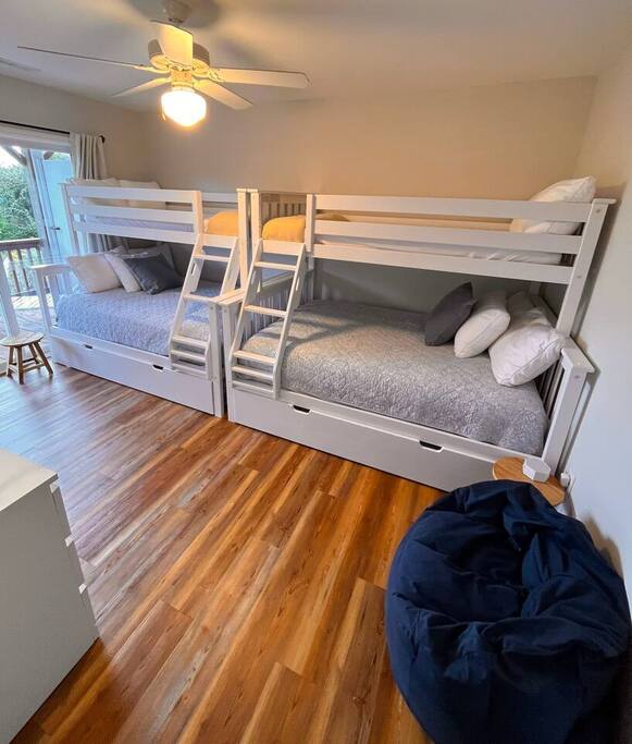 Gather your crew in this bright bunk room featuring custom built-in beds with storage drawers and cozy bedding on warm hardwood floors.