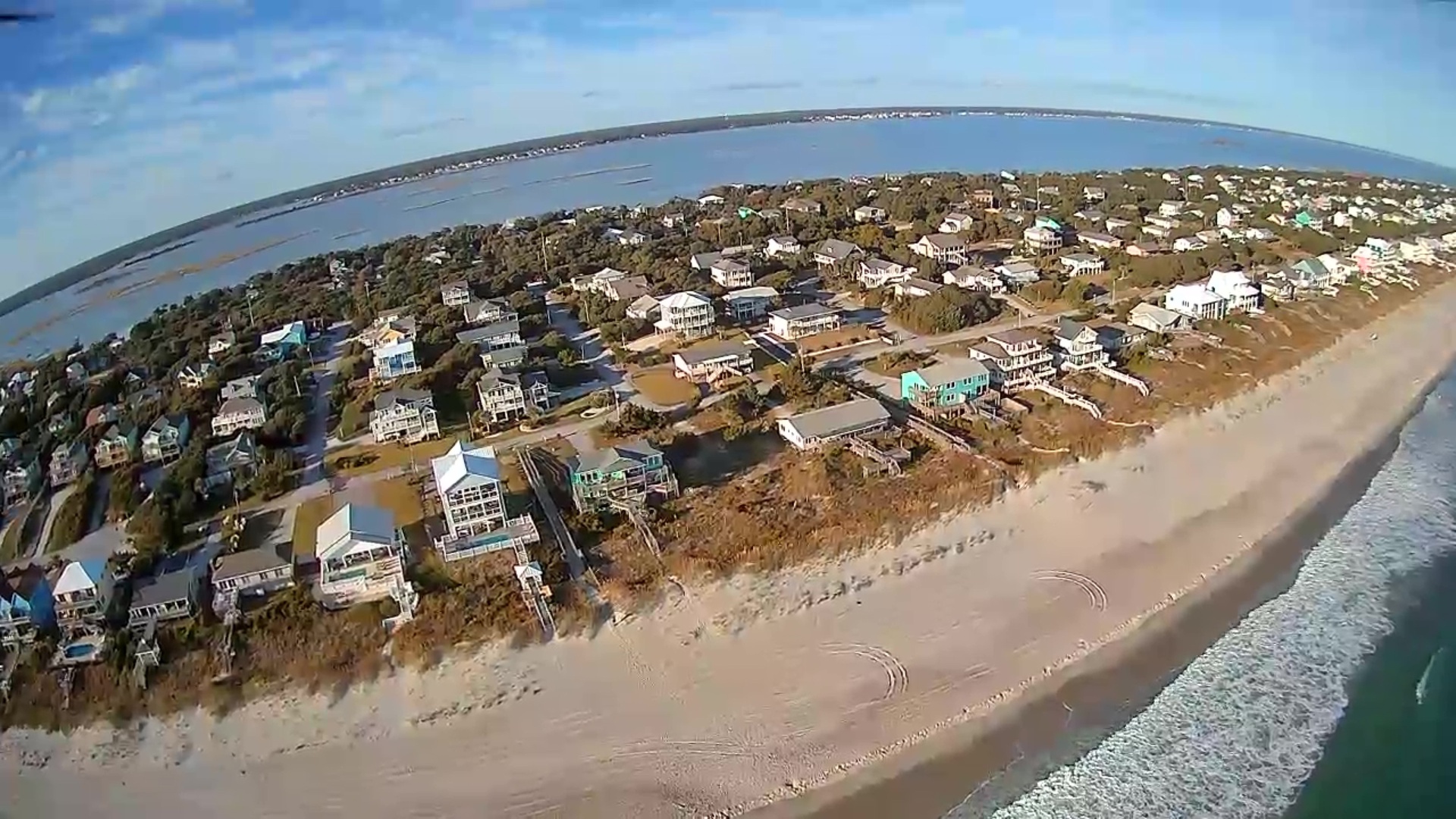 Aerial view of beachfront vacation homes along pristine coastline with sandy beaches and coastal community.
