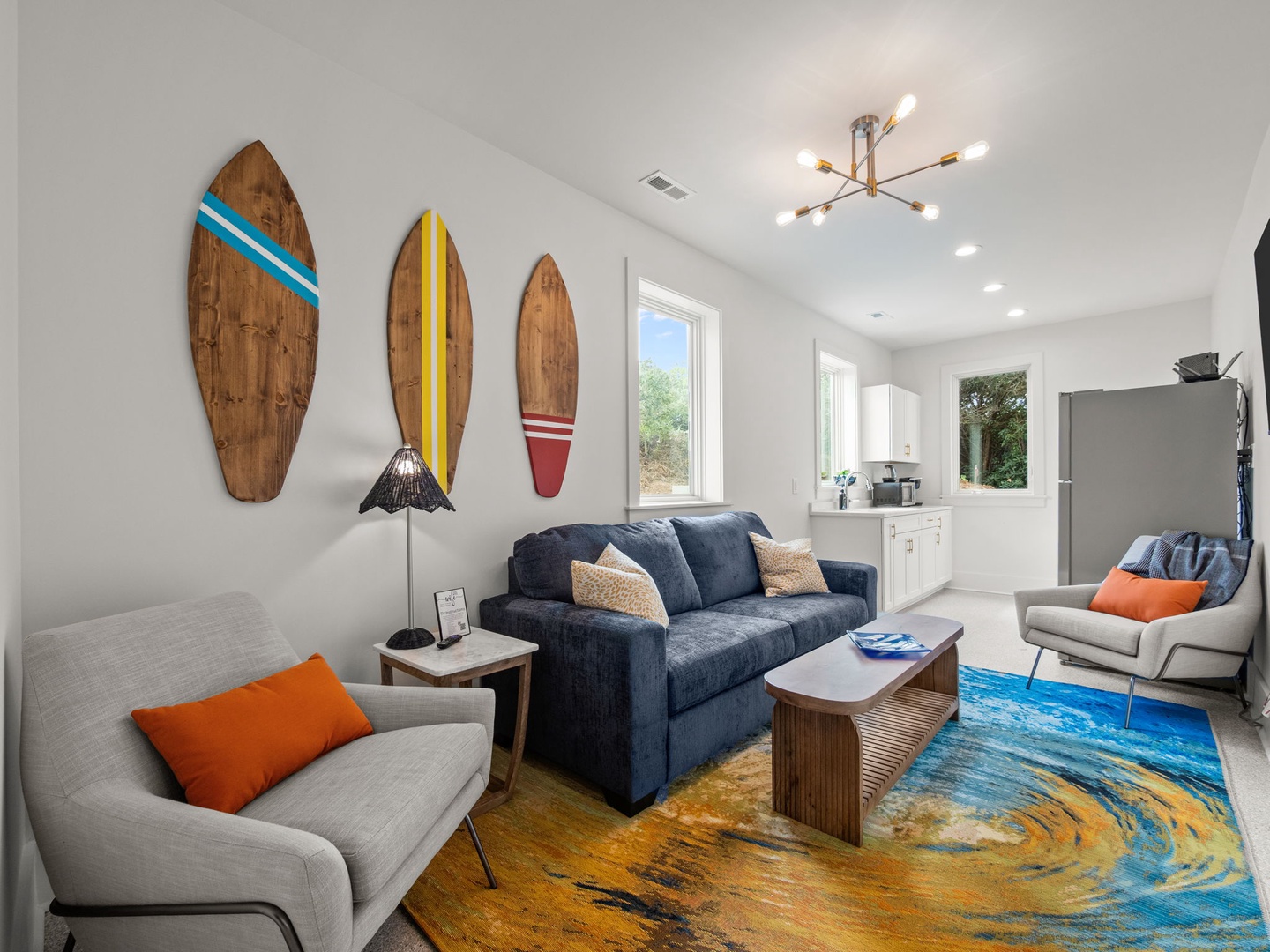 Relax in your coastal-inspired living room with surfboard art, modern lighting, and ocean-wave rug creating the perfect beach house vibe.