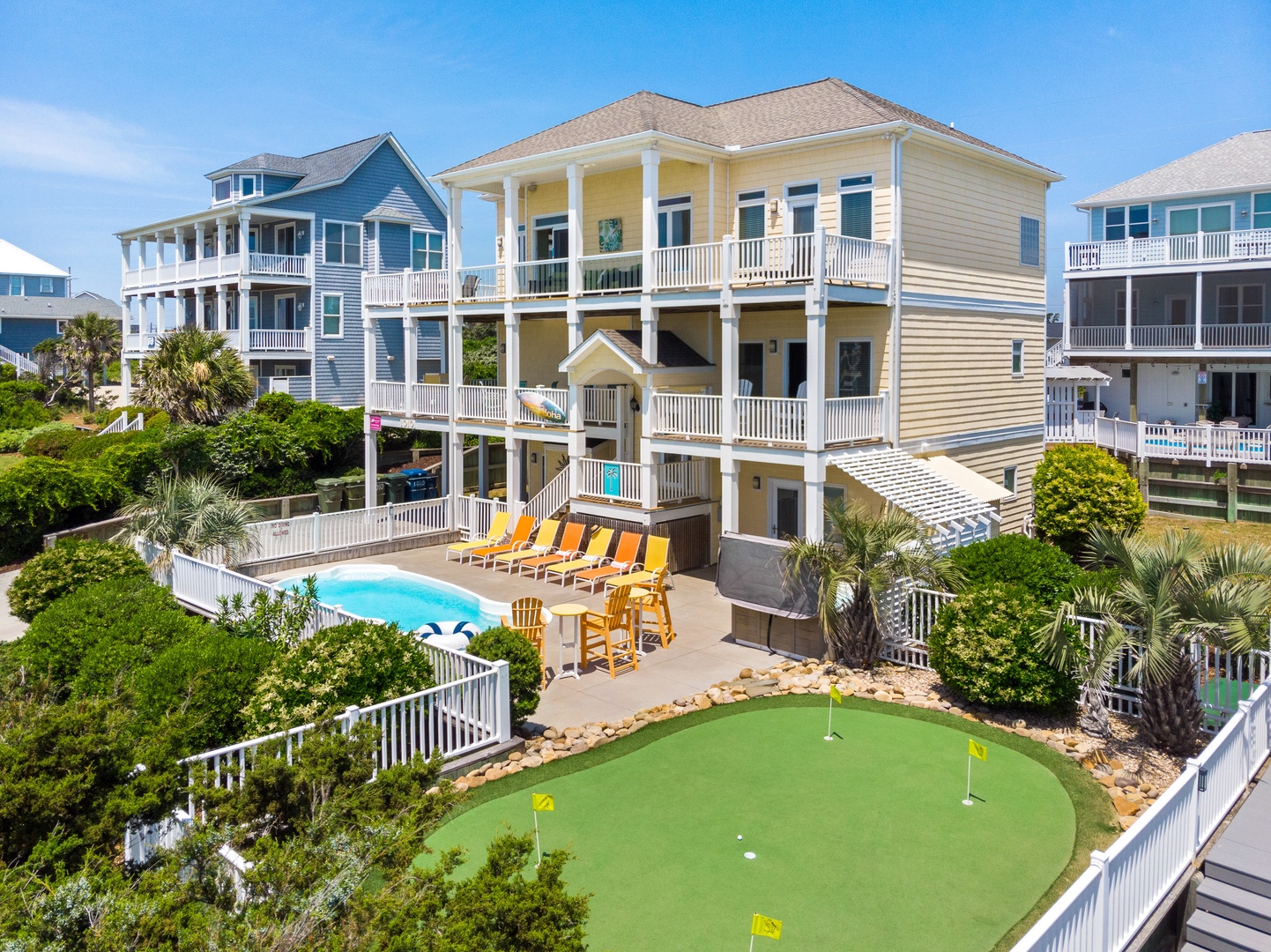 Impressive multi-level beach house with private pool, putting green, and tropical landscaping in a coastal neighborhood.