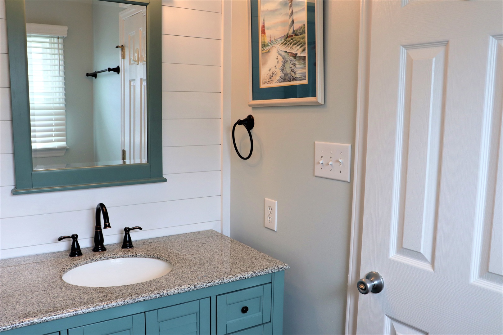 Your charming bathroom features coastal-inspired details with a beautiful turquoise vanity, granite countertop, and nautical artwork creating a peaceful seaside retreat.