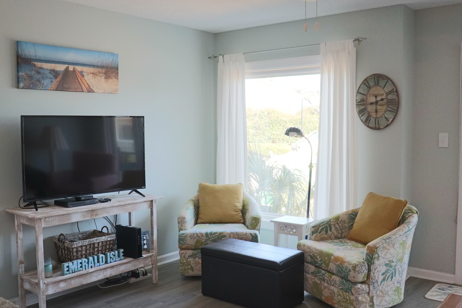 Unwind in your coastal-themed living room with tropical chairs and beach artwork creating the perfect vacation atmosphere.