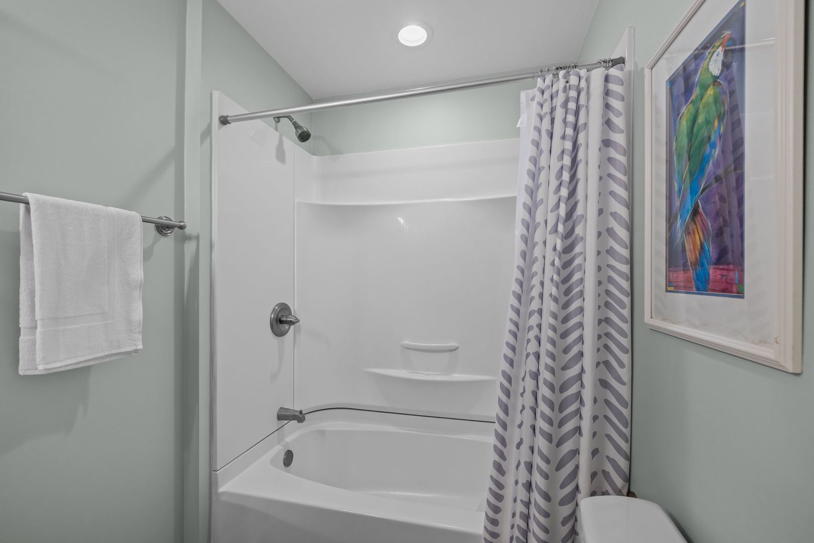 Refresh in your clean, modern bathroom featuring a full tub-shower combo with fresh towels and cheerful artwork.