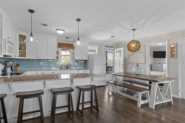 Your beautiful kitchen awaits with white cabinets, pendant lighting, and a cozy dining nook perfect for morning coffee and evening meals together.