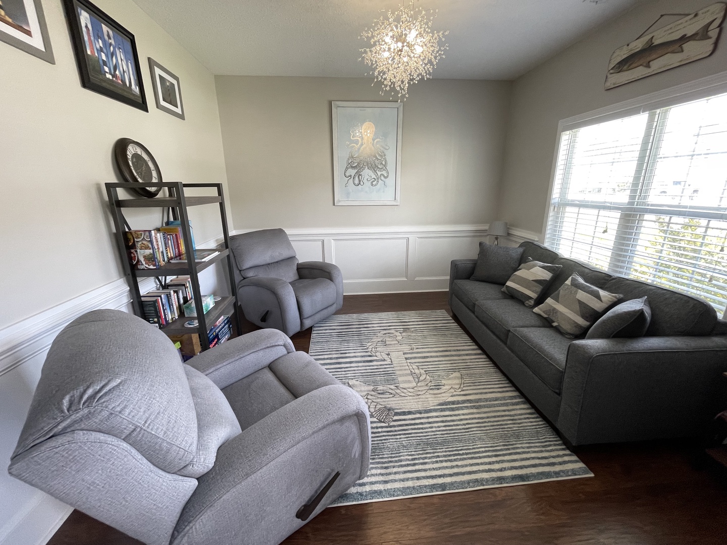 Settle into your elegant living room with plush gray seating, sparkling chandelier, and city views through large windows.