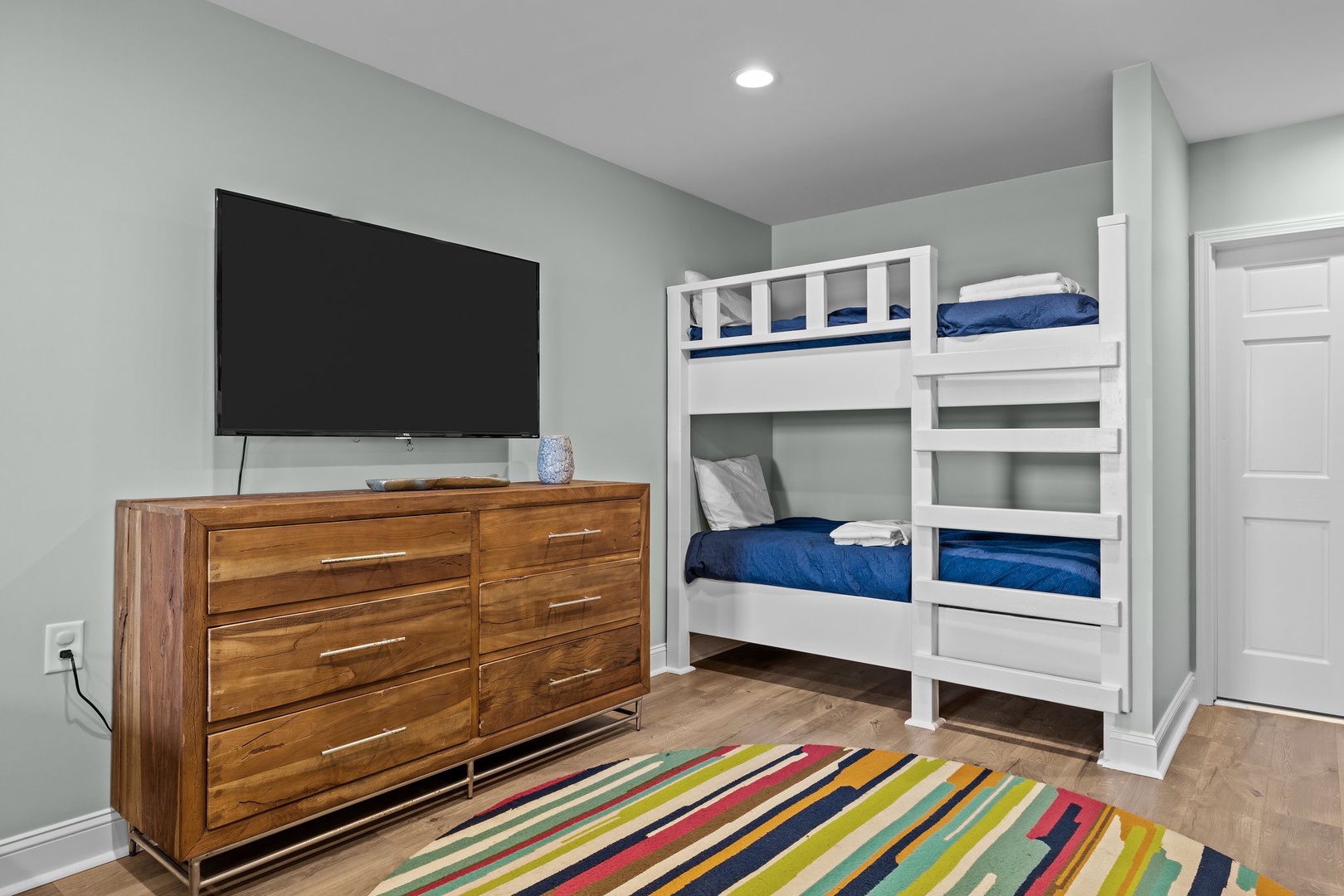 Your kids will love this playful bedroom with custom white bunk beds and cozy blue linens, plus entertainment at their fingertips.