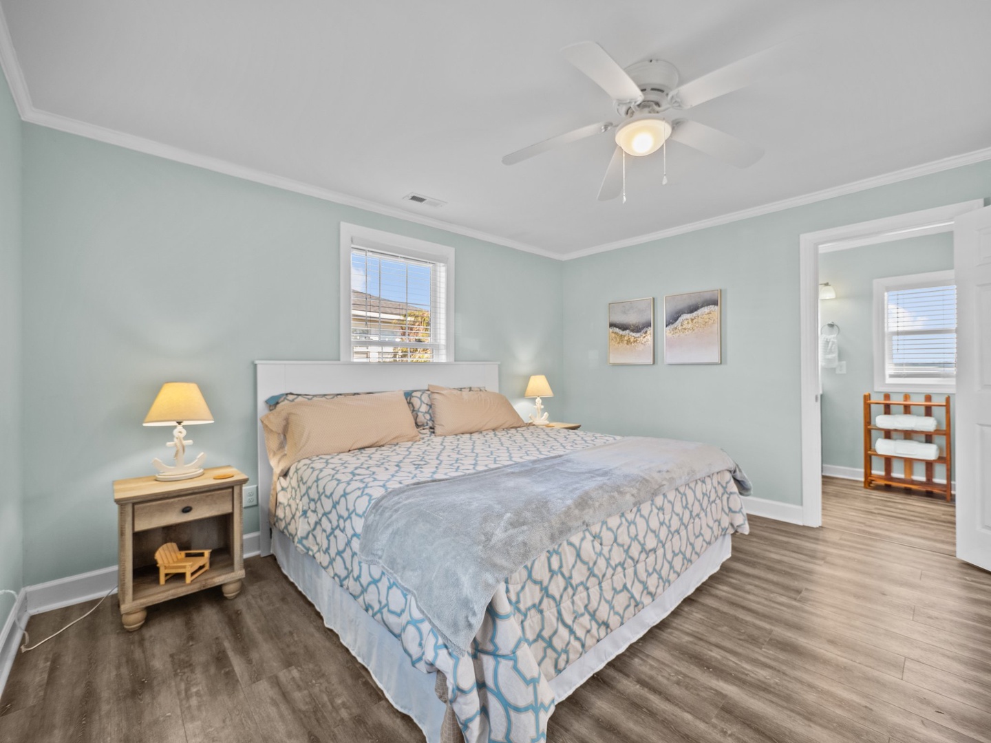 Unwind in your peaceful bedroom with soothing coastal colors, ceiling fan, and natural light streaming through the window.