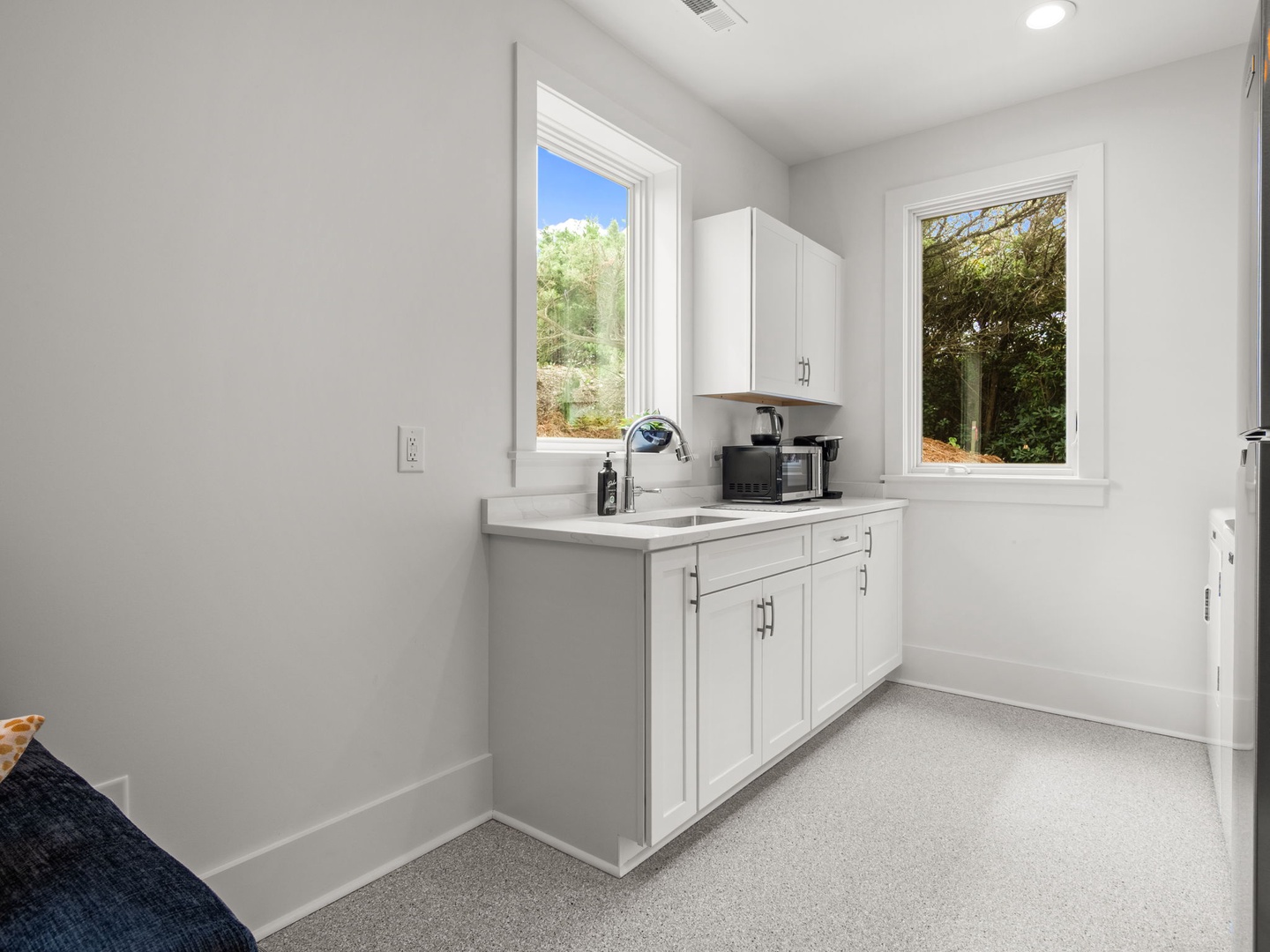 Crisp white kitchenette with modern appliances and leafy garden views—your perfect retreat for morning coffee and light meals.