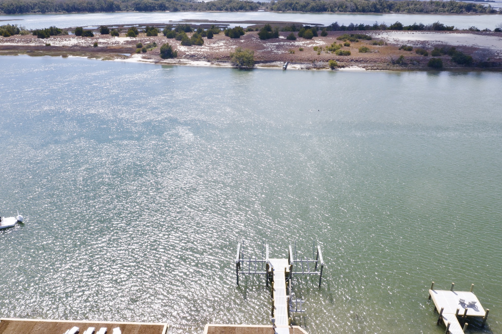 Stunning aerial view of pristine waterfront location with private dock extending into sparkling lake waters surrounded by natural coastline.