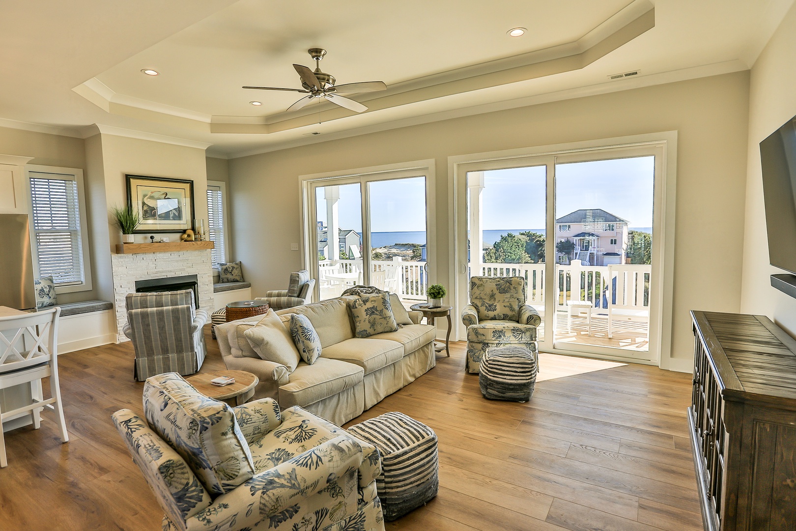 Relax in your coastal living room with comfortable seating, warm fireplace, and stunning sea views through floor-to-ceiling windows.