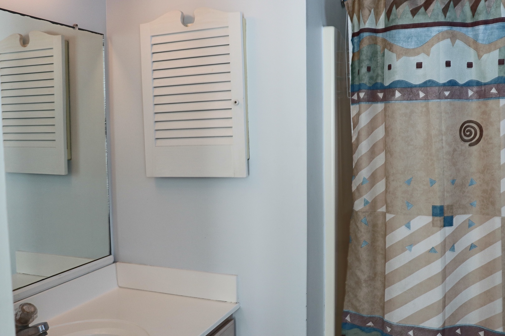 Step into your private bathroom featuring a soothing shower with geometric-patterned curtain and ample storage.
