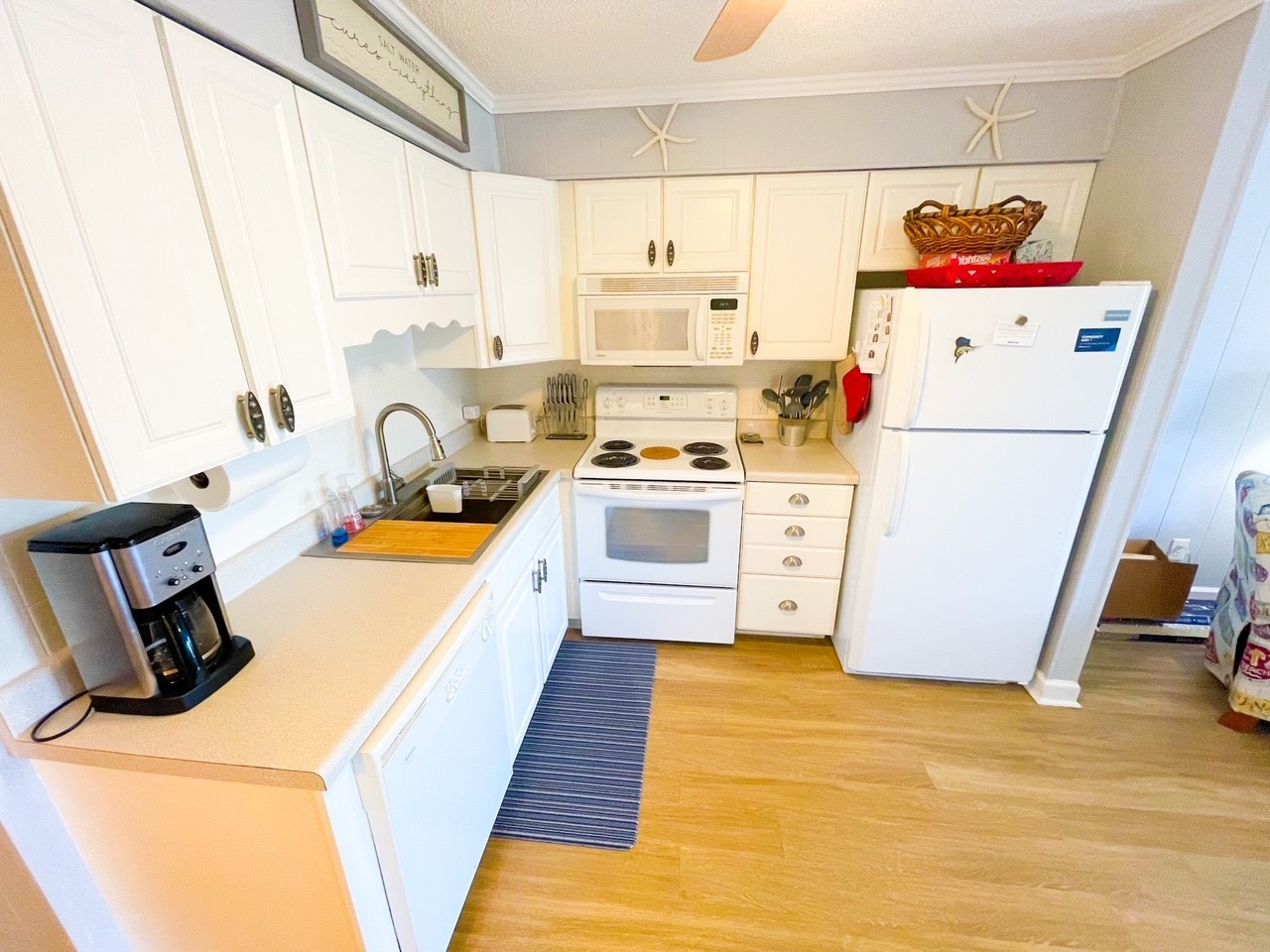 Your fully equipped kitchen awaits with crisp white cabinets, modern appliances, and coastal charm—perfect for preparing meals during your stay.