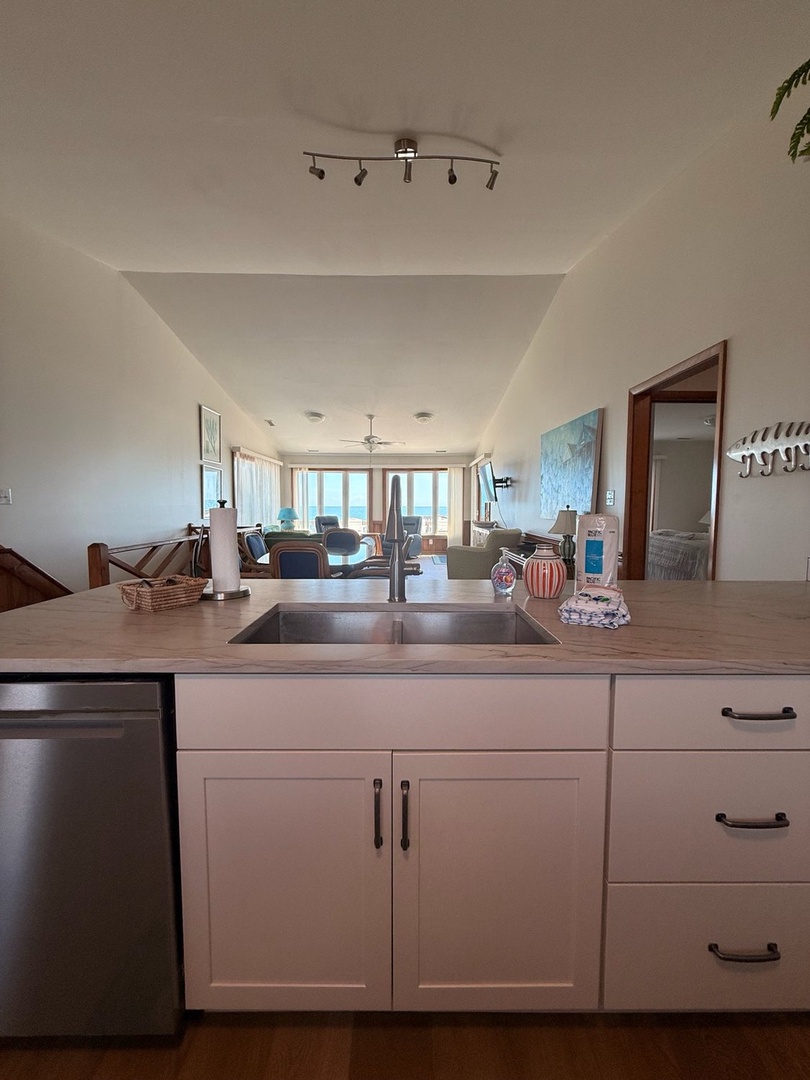 Your open-concept kitchen flows seamlessly into a bright living area with stunning ocean views framing the entire space through expansive windows.