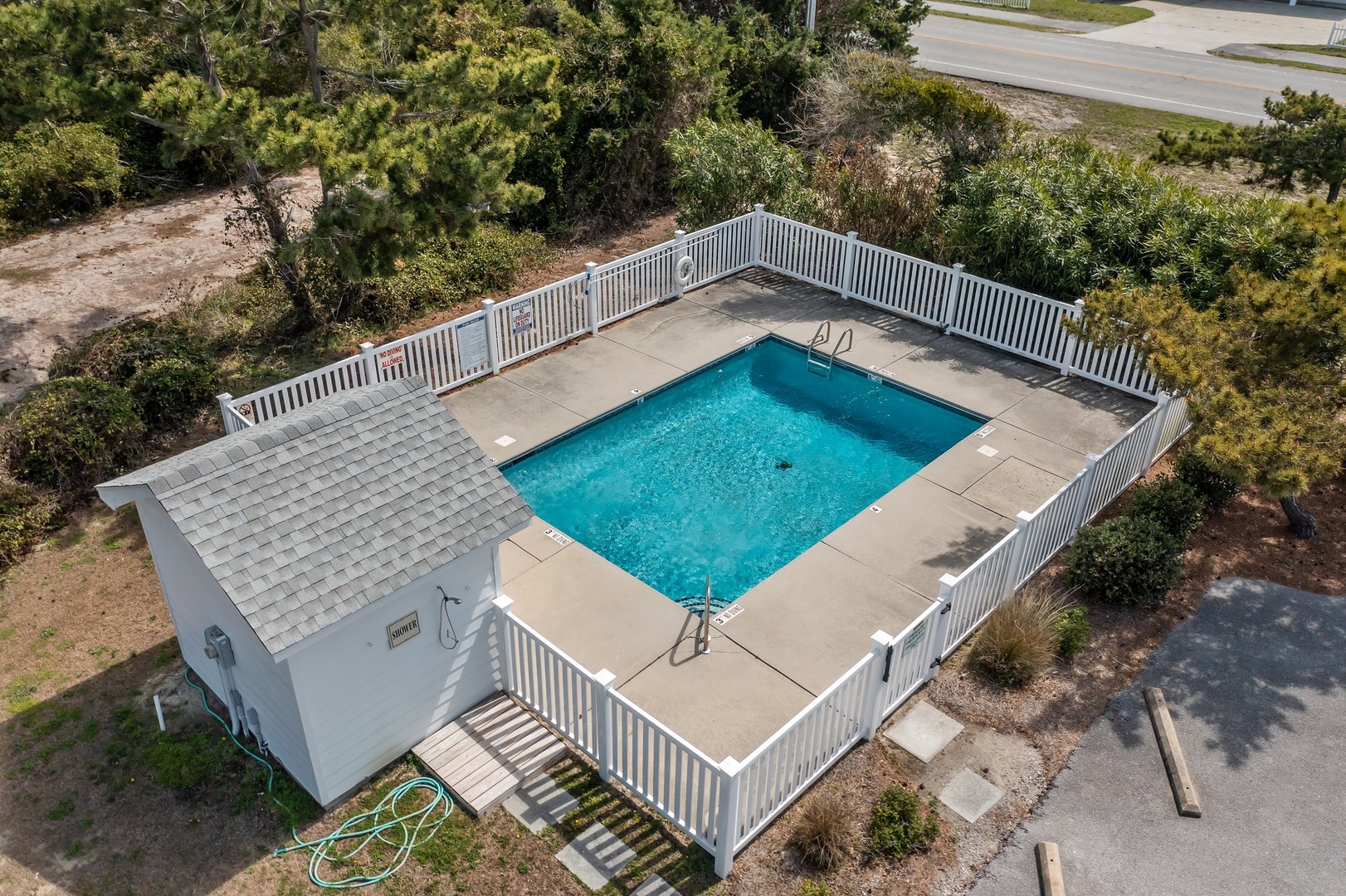 Aerial view of the property featuring a sparkling private swimming pool surrounded by deck space and natural vegetation.