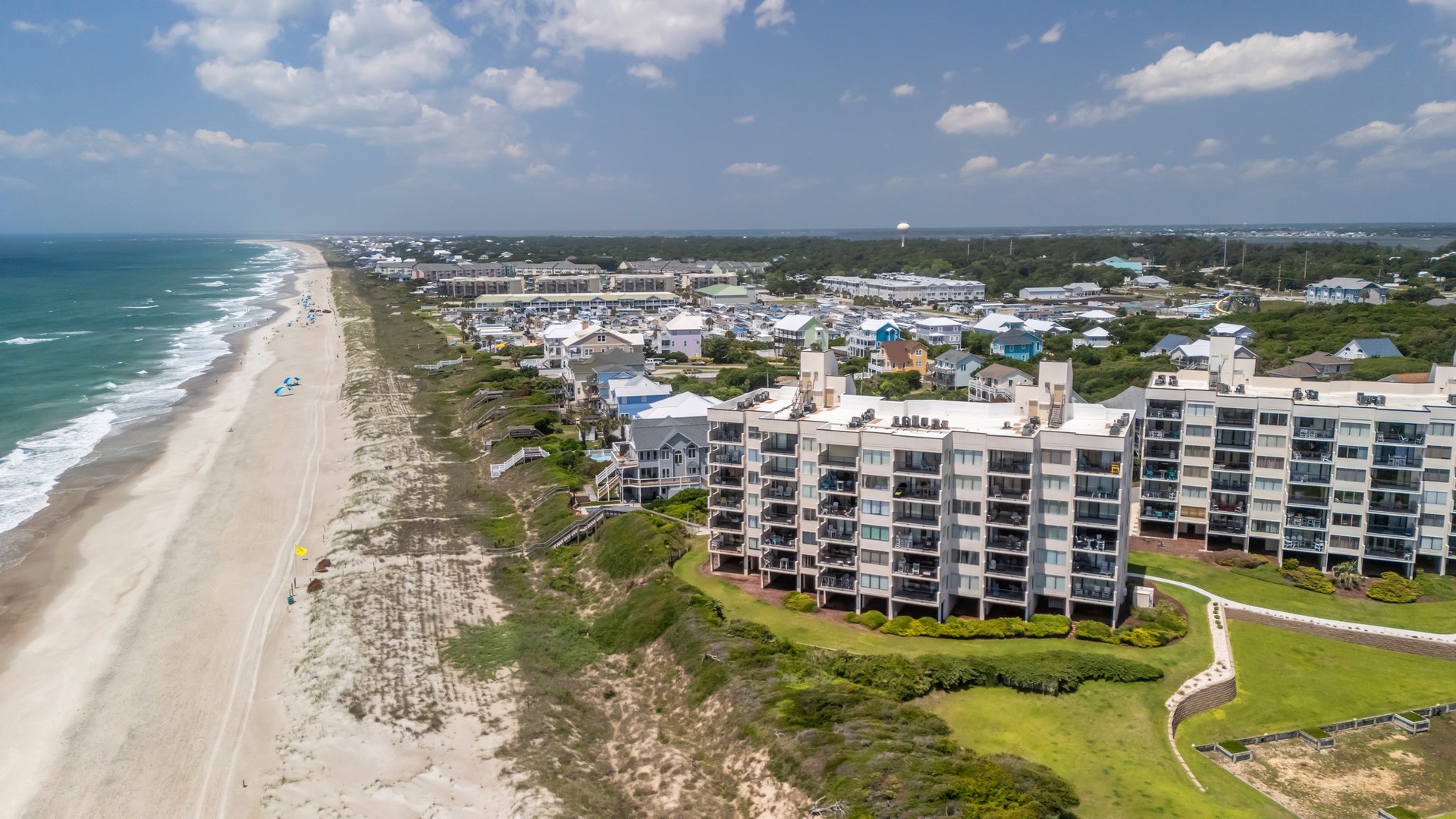 Beachfront condominium complex positioned directly on pristine sandy coastline with expansive ocean views and nearby residential community.