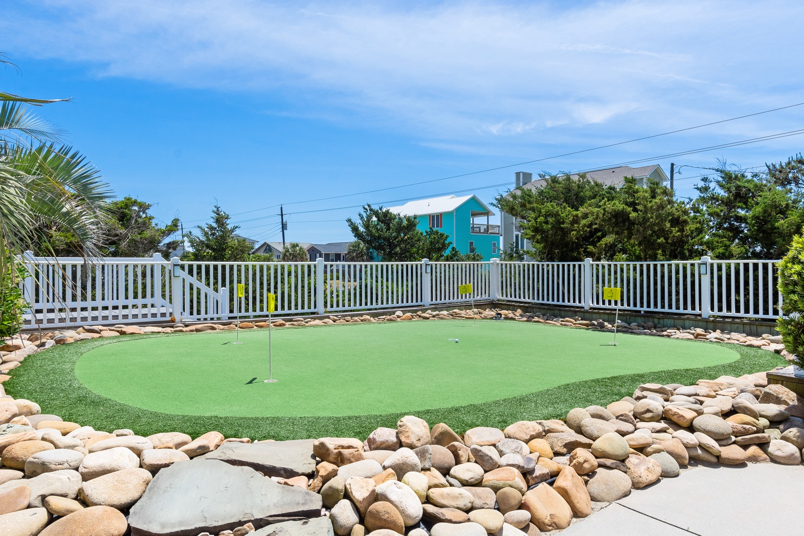 Practice your putting on this beautifully designed mini golf green surrounded by smooth river rocks and tropical palms.