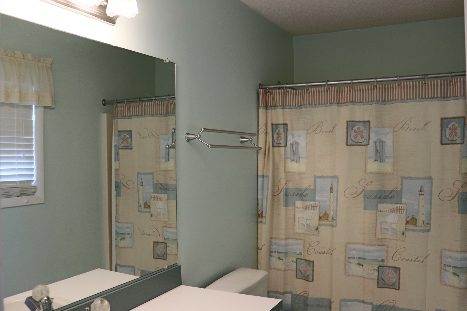 Step into your private coastal-themed bathroom featuring beach-inspired decor and a refreshing shower to start each vacation day renewed.