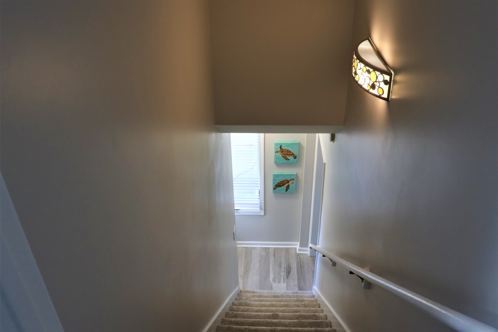 Stylish stairway leads you to your private retreat, with coastal artwork and modern lighting creating a welcoming arrival experience.