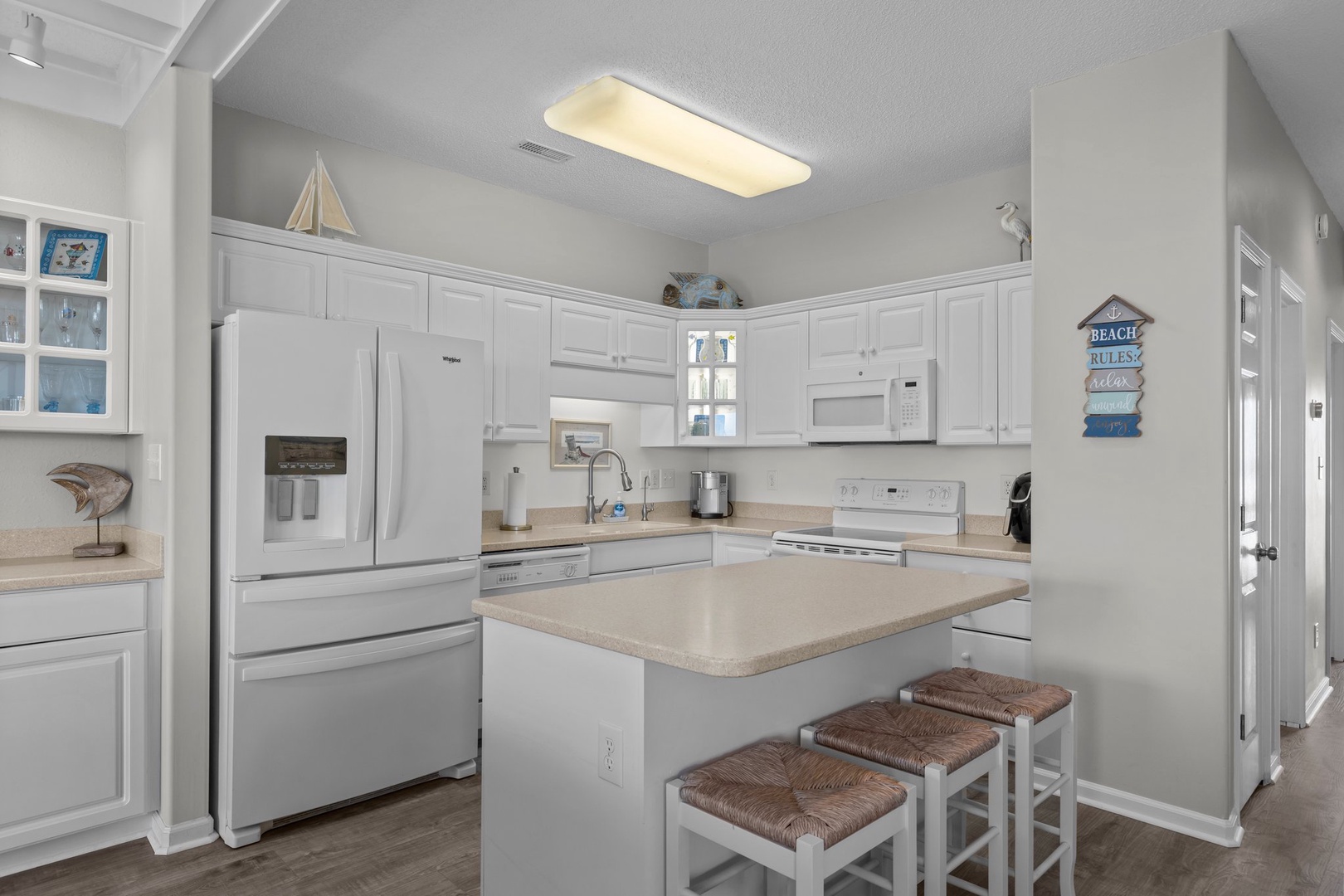 Your bright, fully-equipped kitchen features white appliances and coastal touches, perfect for preparing meals during your beach getaway.