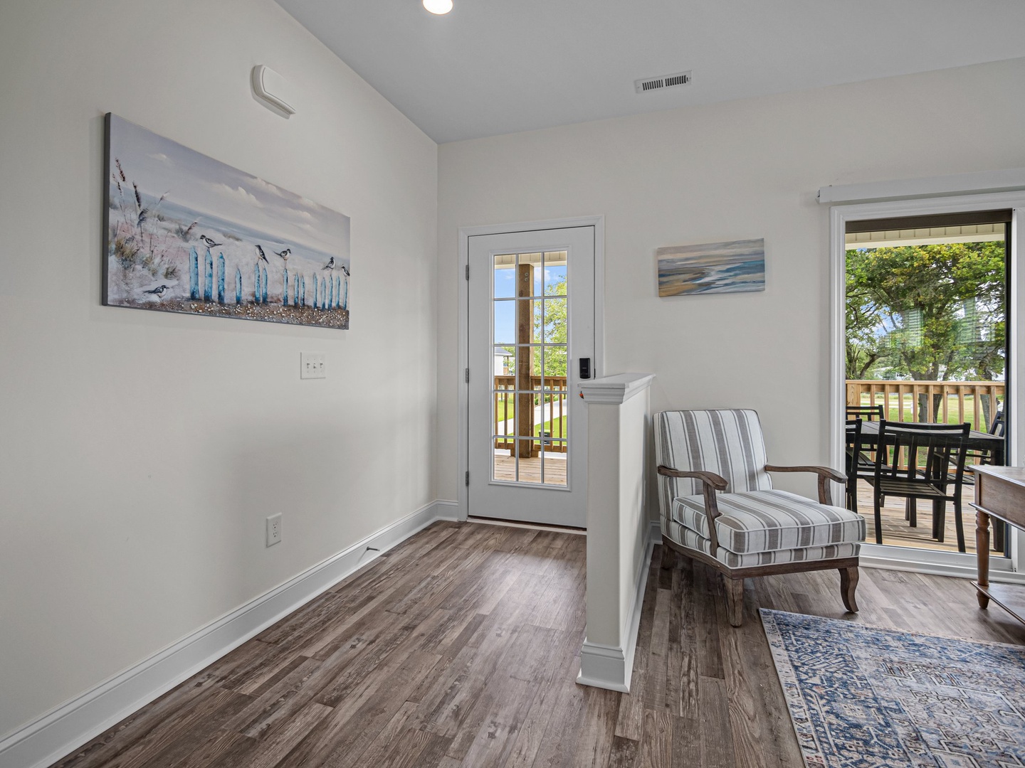 Relax in your bright, coastal-themed space with comfortable seating and private balcony access overlooking peaceful outdoor views.