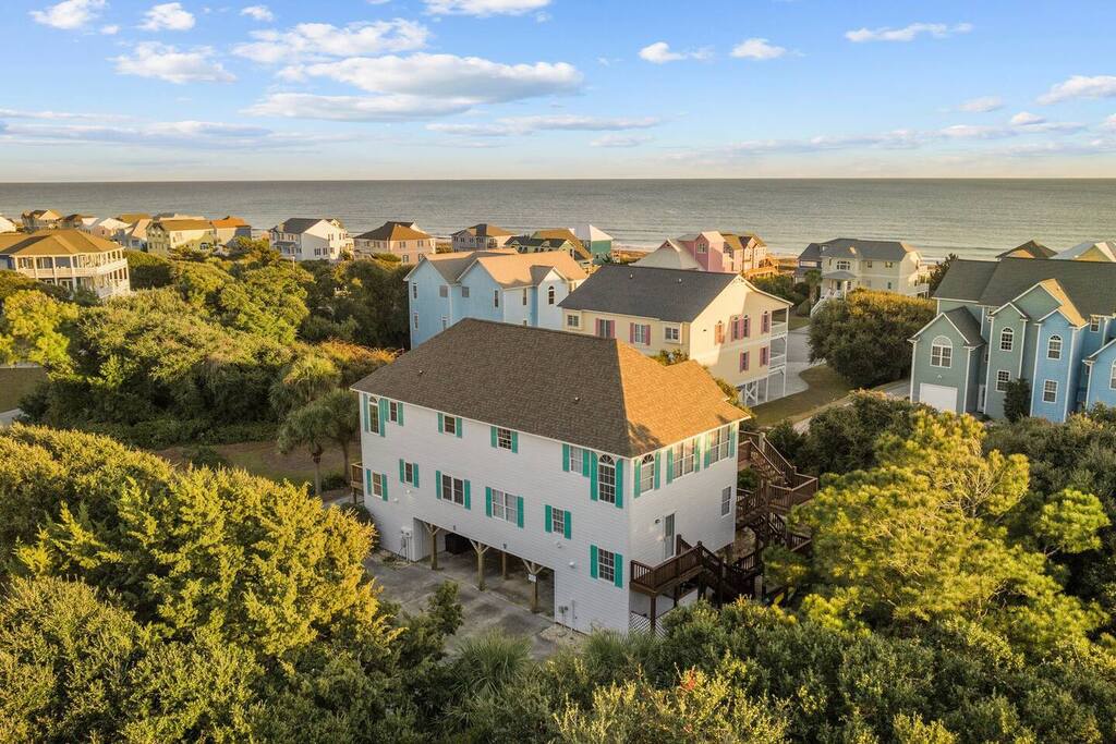 Charming coastal cottage nestled among lush trees, just steps from the ocean in a peaceful beachfront community.
