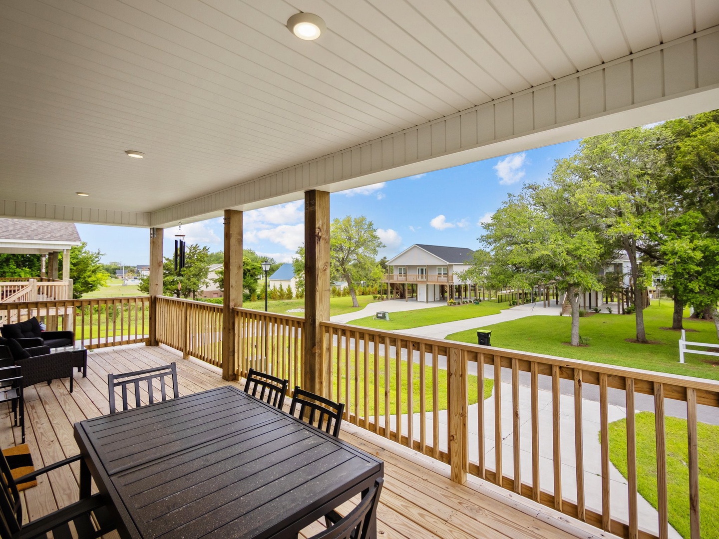 Relax on your spacious covered deck with dining table and seating, overlooking the peaceful green lawn and neighborhood.