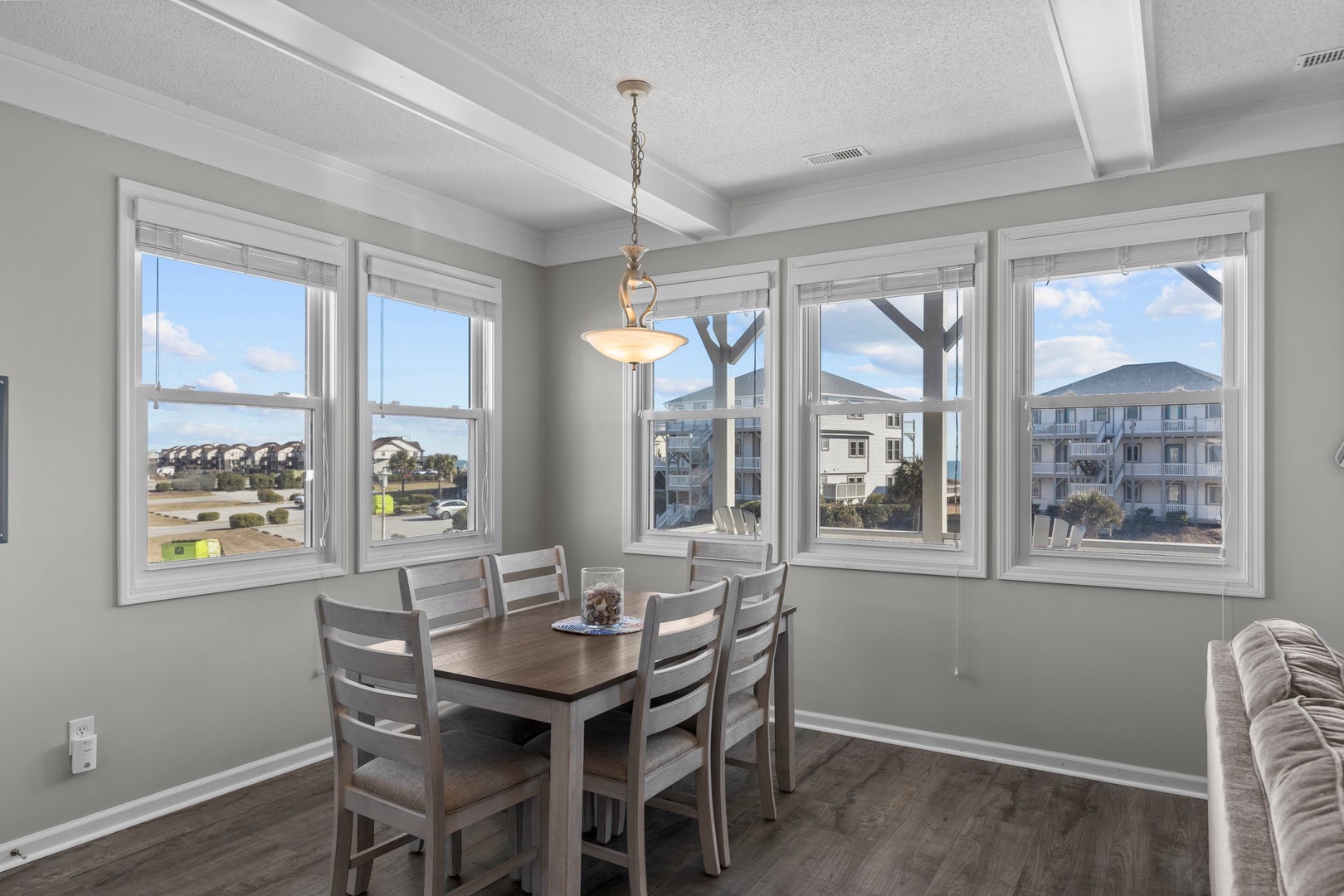 Gather around your bright dining table surrounded by windows showcasing coastal views, where morning coffee and evening meals feel extra special.