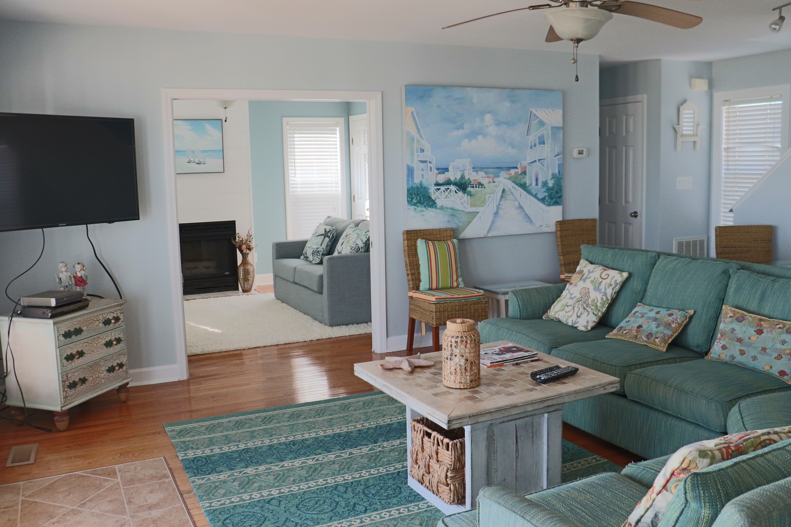 Sink into coastal comfort in your bright living room, where turquoise hues and beach artwork create the perfect seaside retreat.