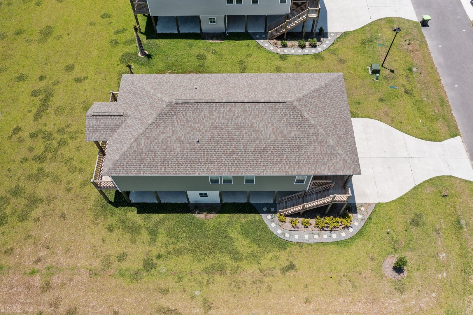 Aerial view of property situated in a peaceful residential neighborhood with well-maintained landscaping and convenient driveway access.