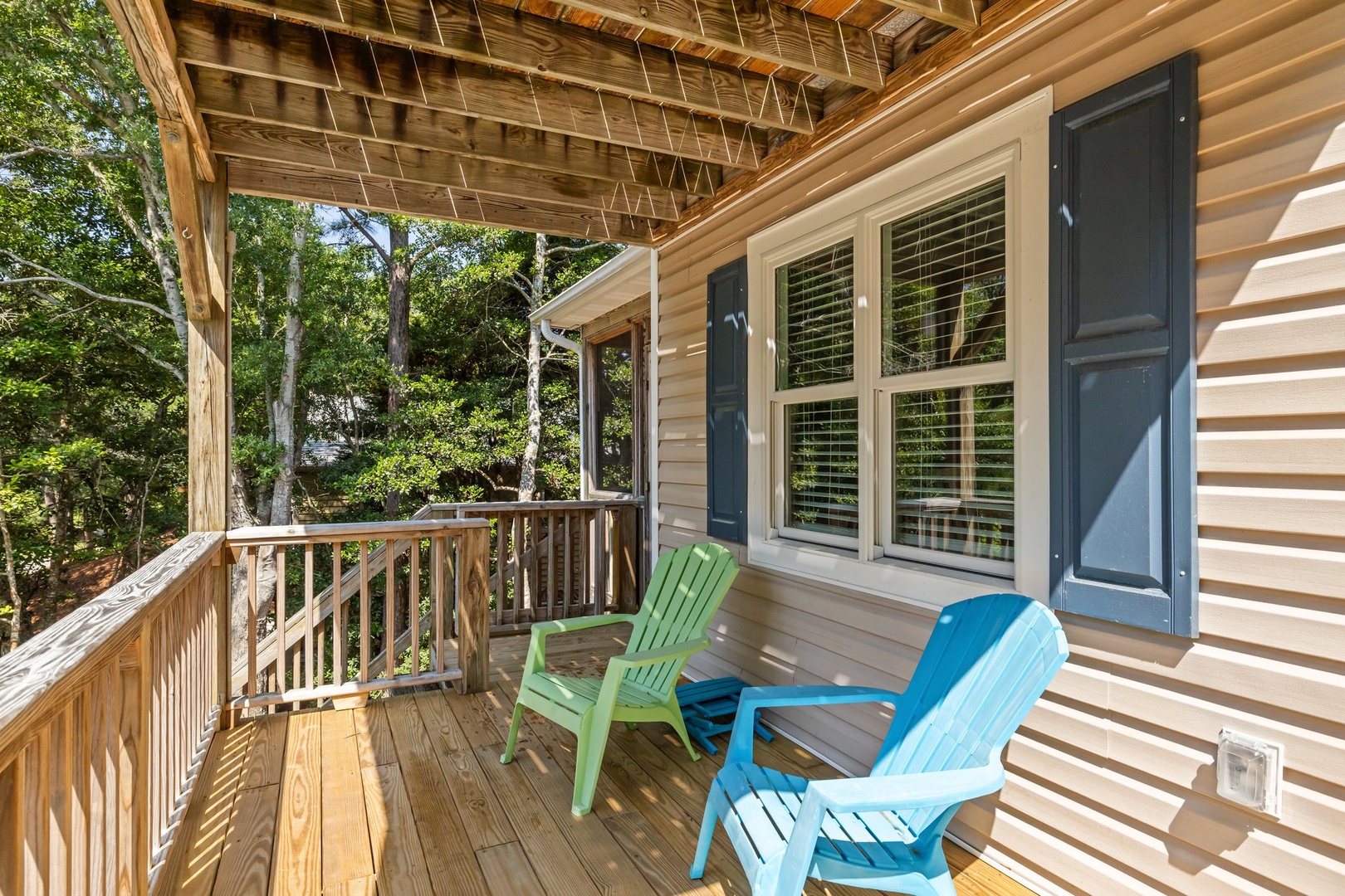 Relax on your private covered deck, where colorful Adirondack chairs await under dappled sunlight and leafy canopy views.