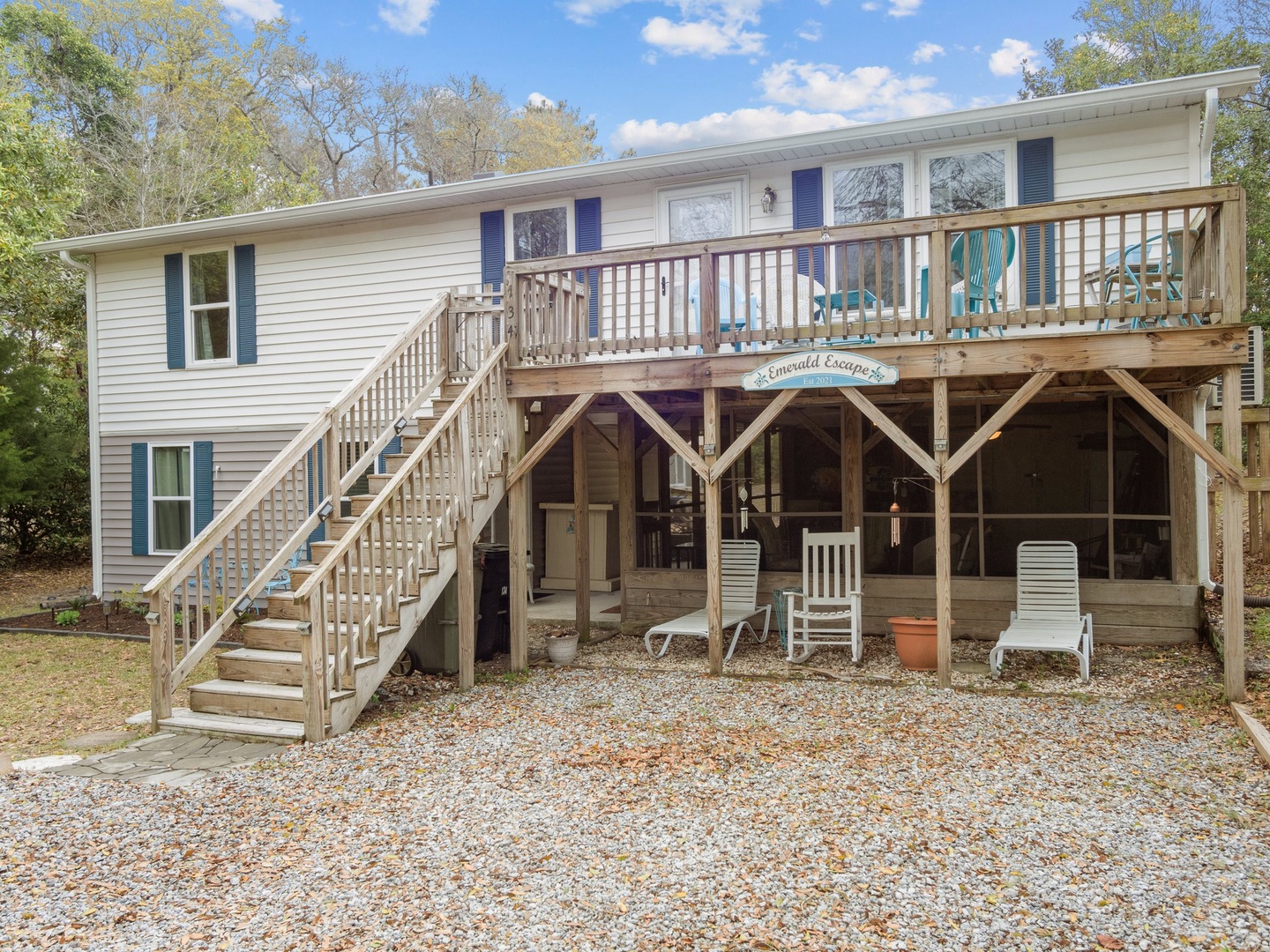 Charming coastal retreat featuring a spacious upper deck and covered ground-level patio, surrounded by mature trees for natural privacy.